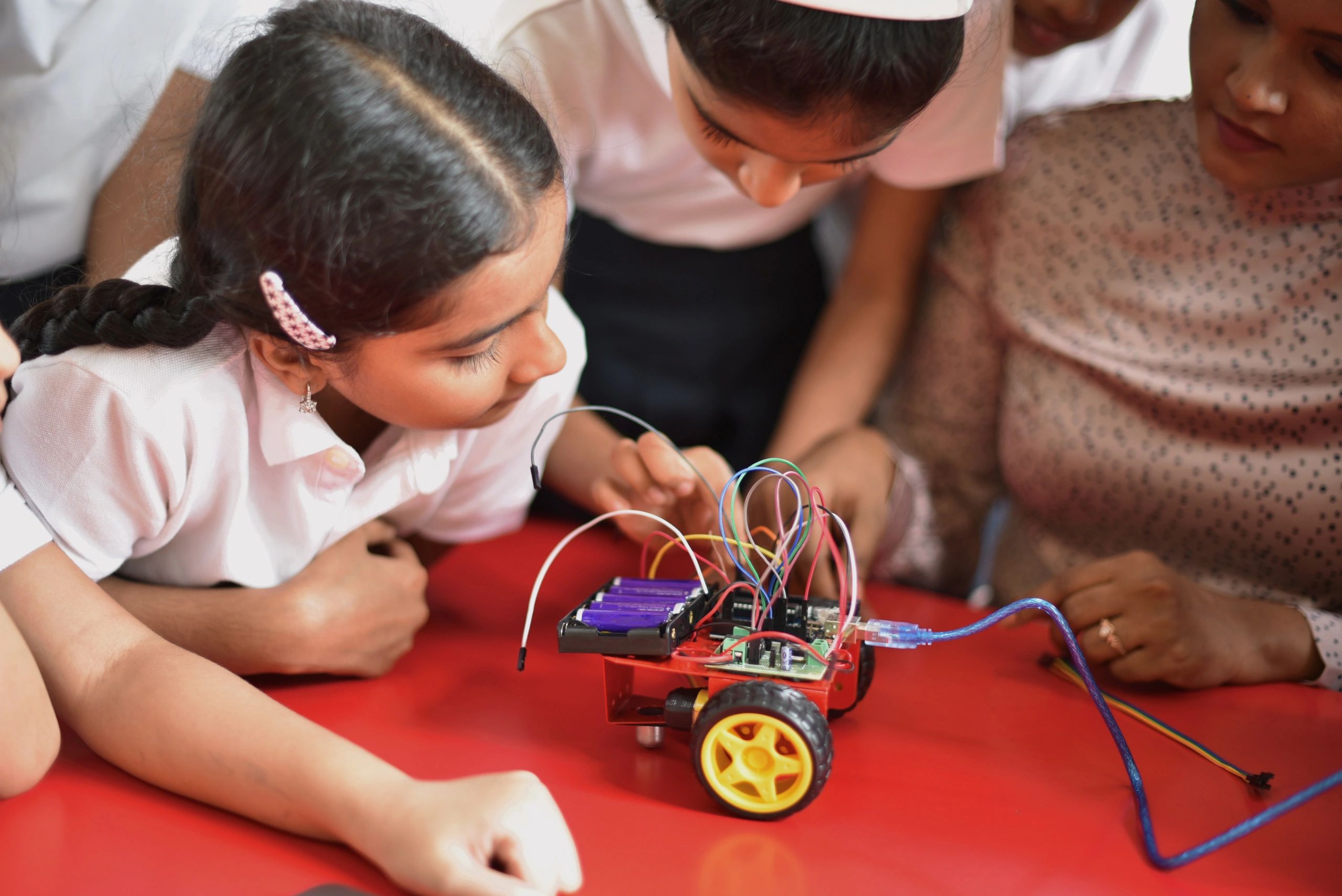 Students building a robotics project with a teacher