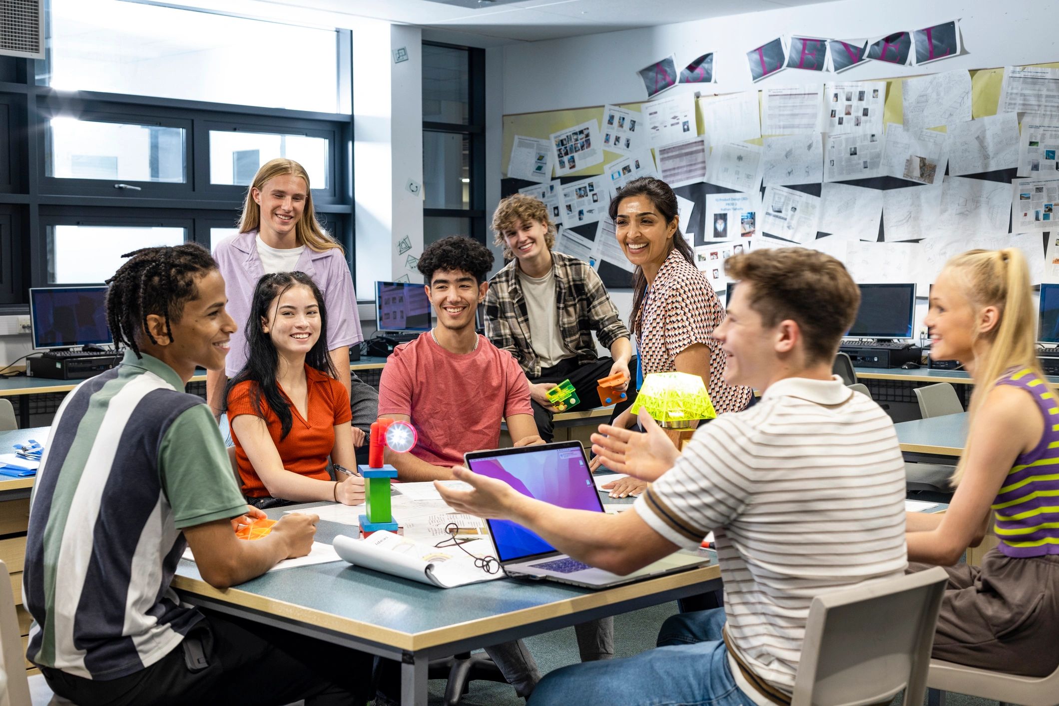 Teacher and students collaborating and laughing in a classroom