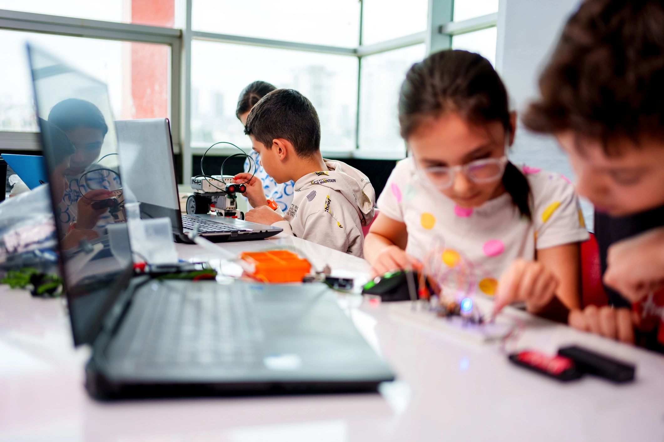 Students collaborating on a robotics STEM project with laptops